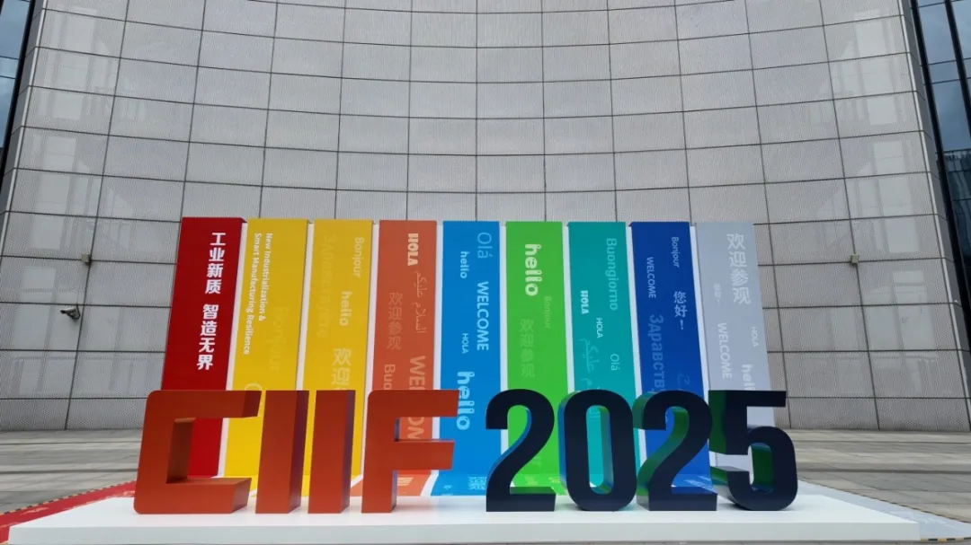 Colorful “CIIF 2025” sculpture on a white base, surrounded by vibrant banners reading “WELCOME” И global exhibition themes.